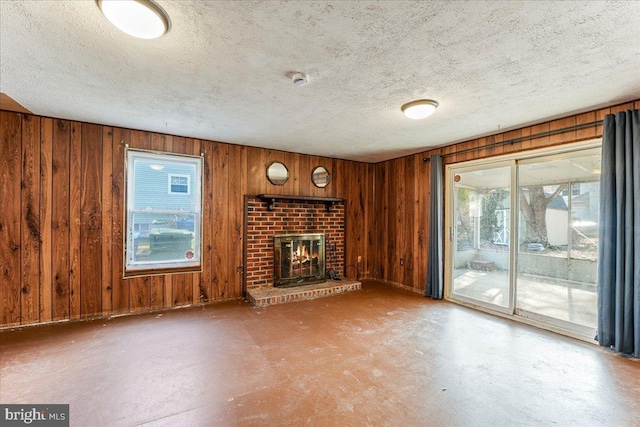 unfurnished living room featuring wood walls, a textured ceiling, and a fireplace