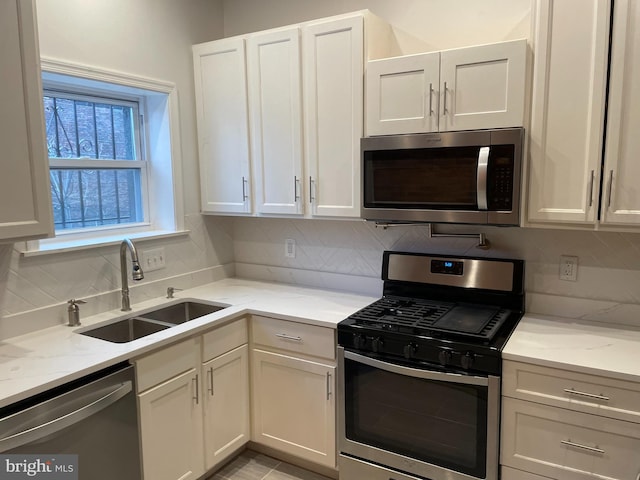 kitchen with stainless steel appliances, white cabinetry, sink, and backsplash