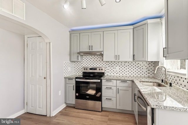 kitchen featuring arched walkways, visible vents, appliances with stainless steel finishes, a sink, and under cabinet range hood