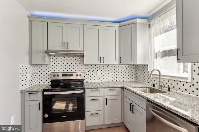 kitchen with stainless steel appliances, backsplash, gray cabinetry, a sink, and under cabinet range hood