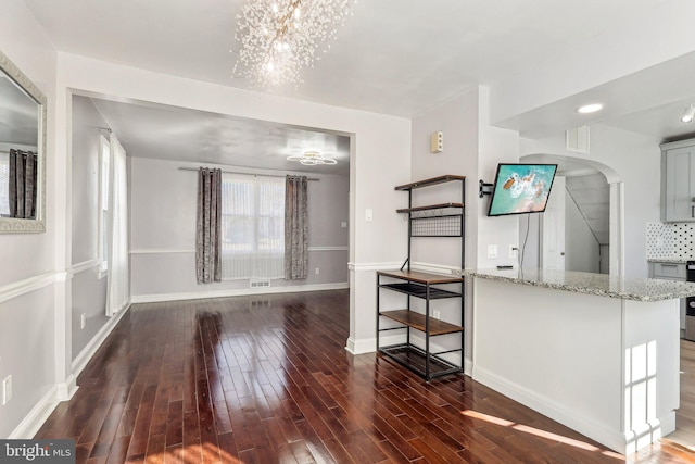 interior space with baseboards, visible vents, light stone counters, and wood finished floors