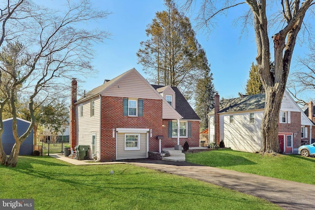 view of front of house with a front lawn, a chimney, fence, and brick siding