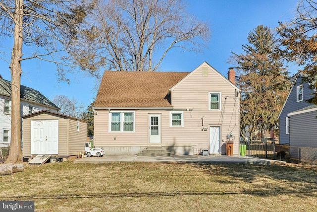 rear view of house with entry steps, an outdoor structure, fence, a yard, and a storage unit