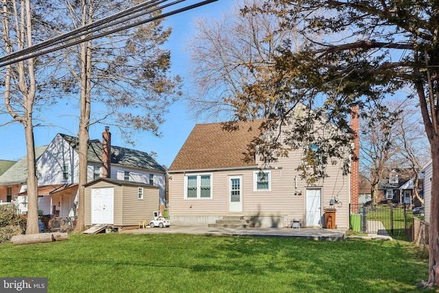 back of house featuring an outbuilding, a lawn, entry steps, fence, and a shed