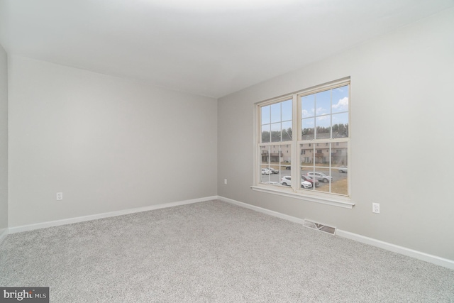 empty room featuring visible vents, baseboards, and carpet