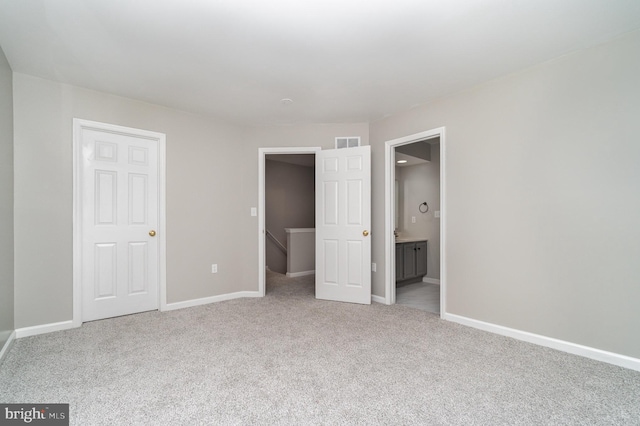 unfurnished bedroom with visible vents, a walk in closet, connected bathroom, carpet flooring, and baseboards