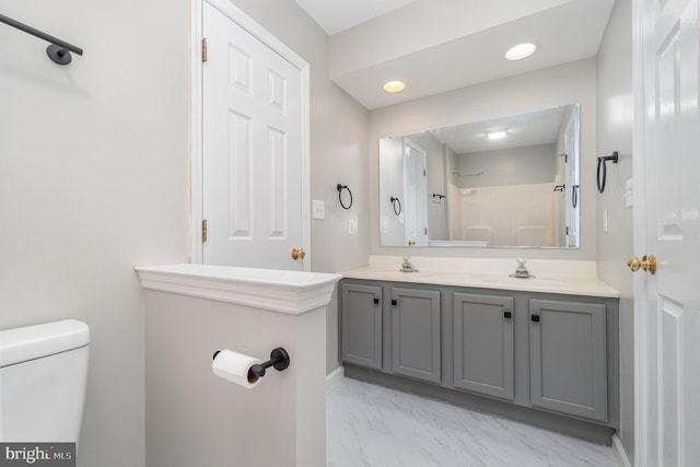 bathroom featuring double vanity, toilet, marble finish floor, and a sink