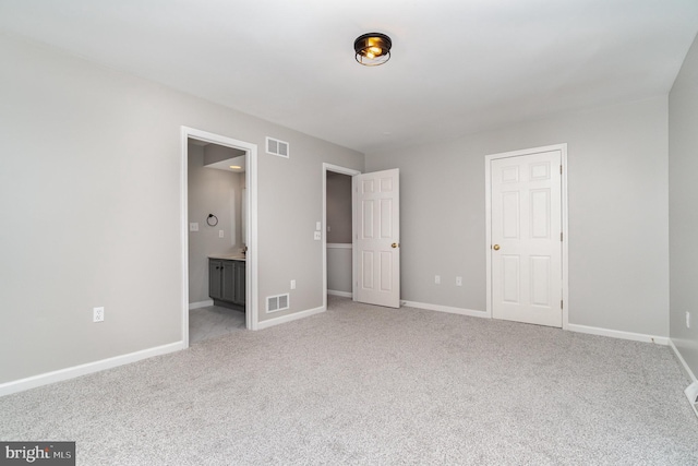 unfurnished bedroom with connected bathroom, baseboards, visible vents, and light carpet