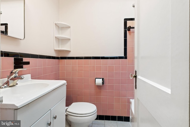 bathroom featuring tile patterned floors, vanity, toilet, and tile walls