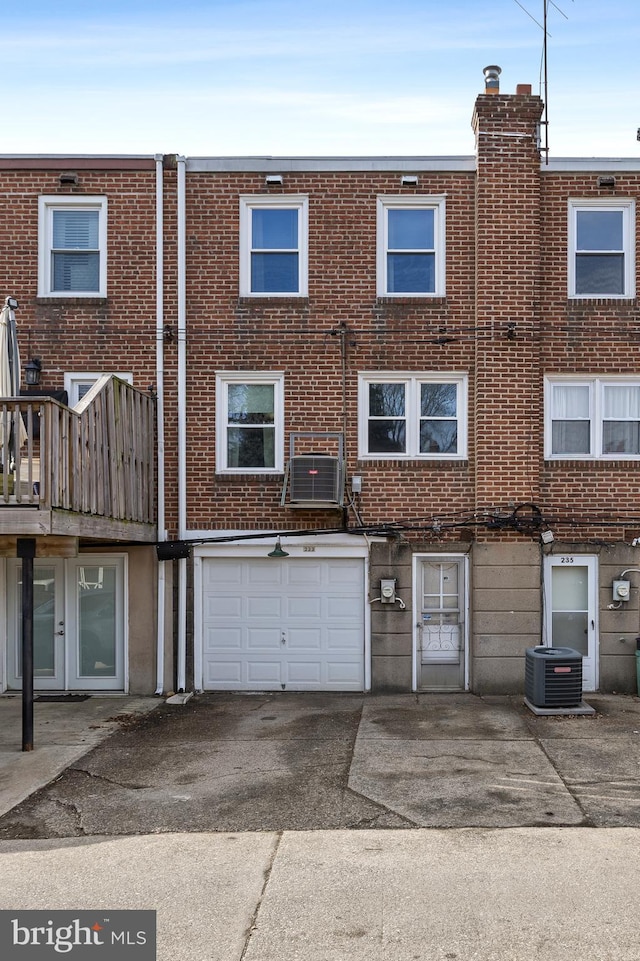 rear view of property featuring central AC and a garage