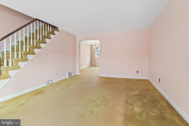 carpeted empty room with an inviting chandelier