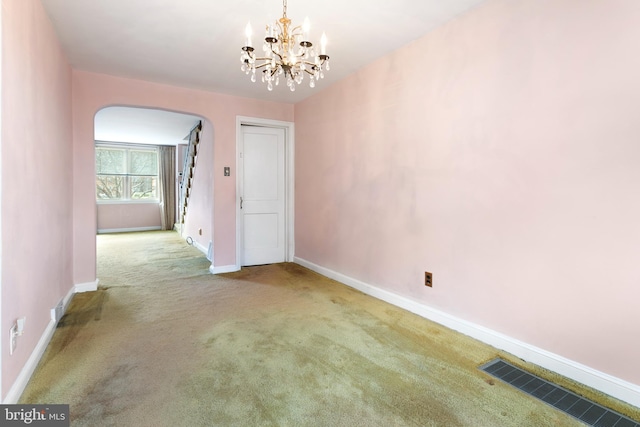 carpeted spare room featuring a chandelier