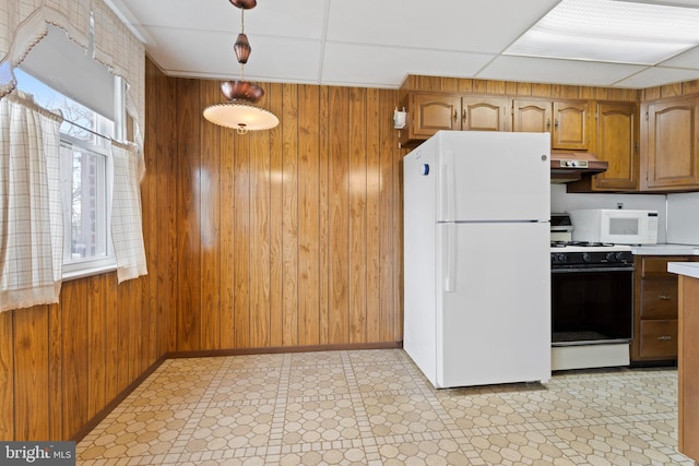 kitchen with a paneled ceiling, wood walls, white appliances, and decorative light fixtures