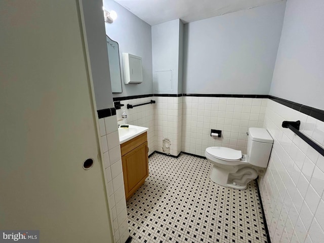 bathroom with tile patterned flooring, vanity, tile walls, and toilet