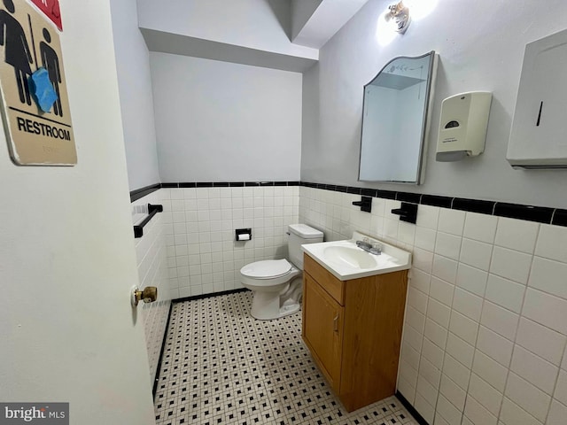 bathroom featuring vanity, toilet, and tile walls