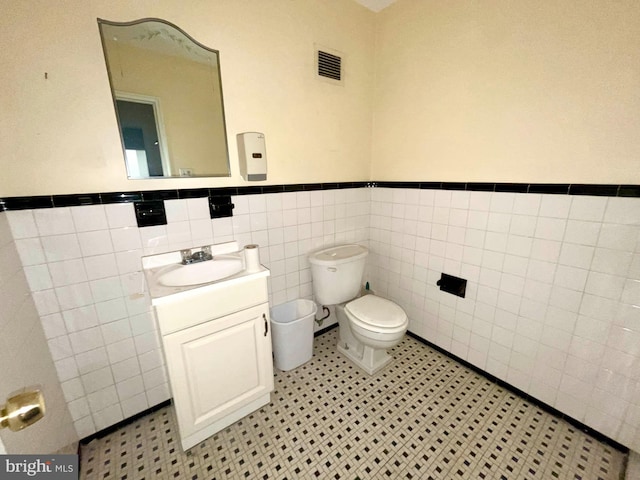 bathroom featuring vanity, tile walls, and toilet