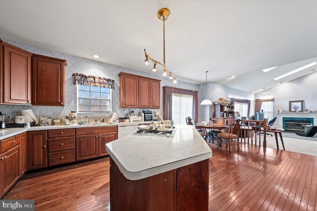 kitchen with pendant lighting, vaulted ceiling, a center island, white dishwasher, and dark hardwood / wood-style floors