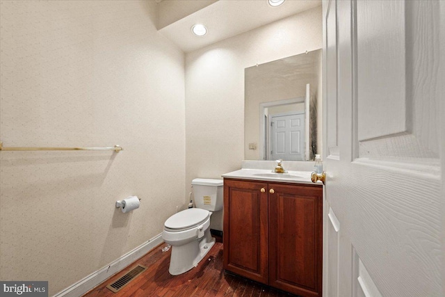 bathroom with wood-type flooring, vanity, and toilet