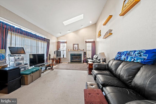 carpeted living room with high vaulted ceiling, a high end fireplace, and a skylight