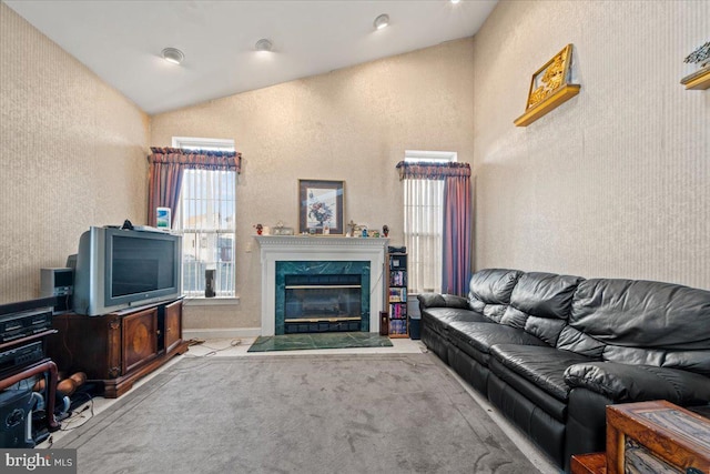 carpeted living room featuring vaulted ceiling and a high end fireplace