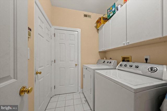 clothes washing area with cabinets, independent washer and dryer, and light tile patterned floors