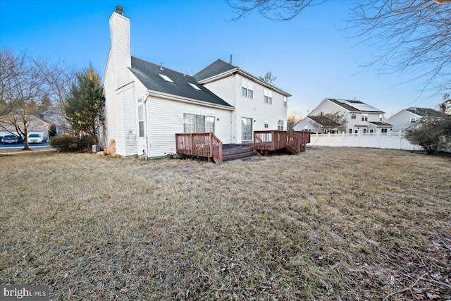 rear view of house featuring a yard and a deck