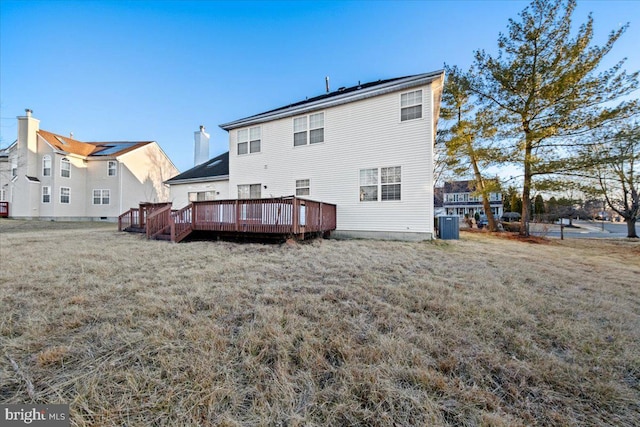 rear view of house with a deck, central AC unit, and a lawn