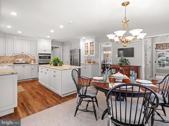 dining room featuring sink, light wood-type flooring, and a notable chandelier