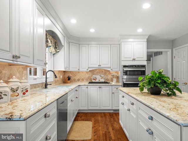 kitchen with appliances with stainless steel finishes, white cabinetry, sink, backsplash, and dark wood-type flooring