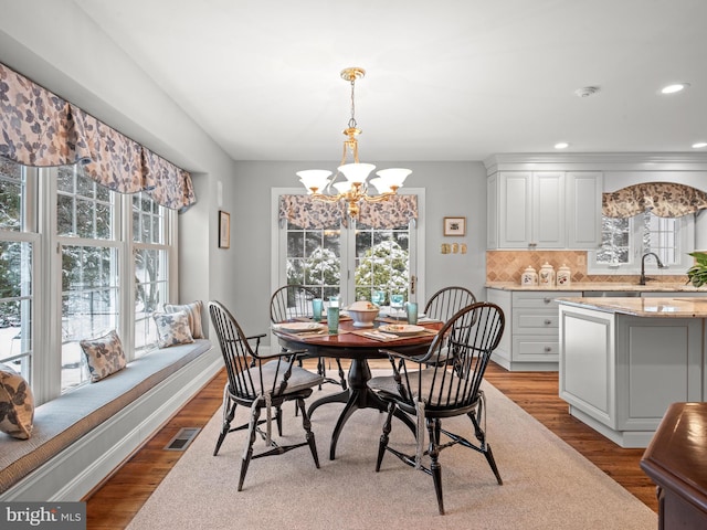 dining space with a notable chandelier, light hardwood / wood-style flooring, and sink