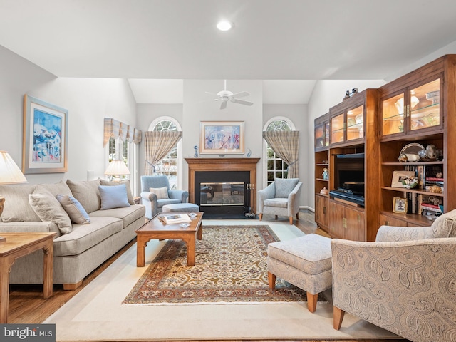 living room with ceiling fan, lofted ceiling, a healthy amount of sunlight, and light wood-type flooring