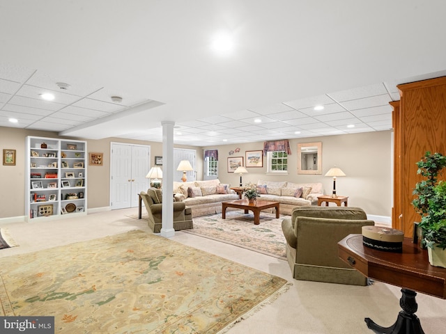 carpeted living room with a drop ceiling and decorative columns