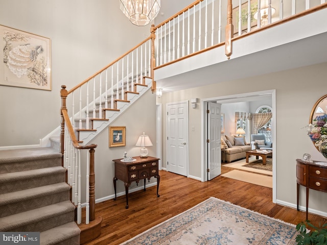 stairway featuring wood-type flooring, a chandelier, and a high ceiling