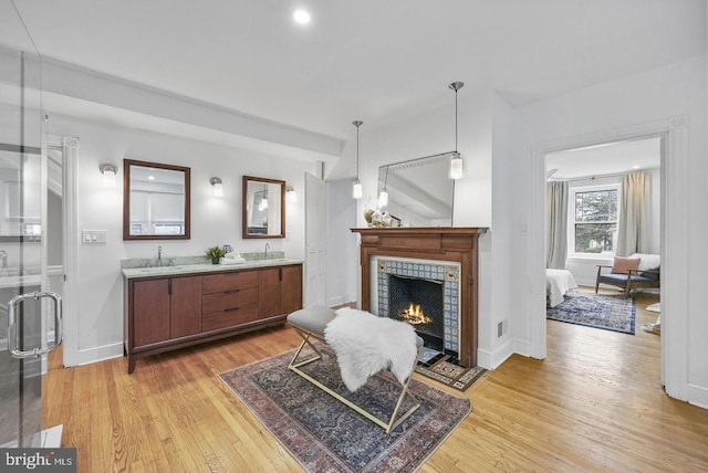 living area featuring sink, light hardwood / wood-style floors, and a tile fireplace