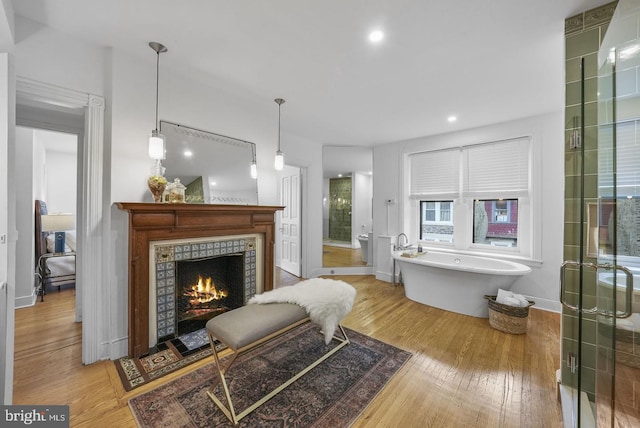 bathroom featuring a tile fireplace, shower with separate bathtub, and hardwood / wood-style floors