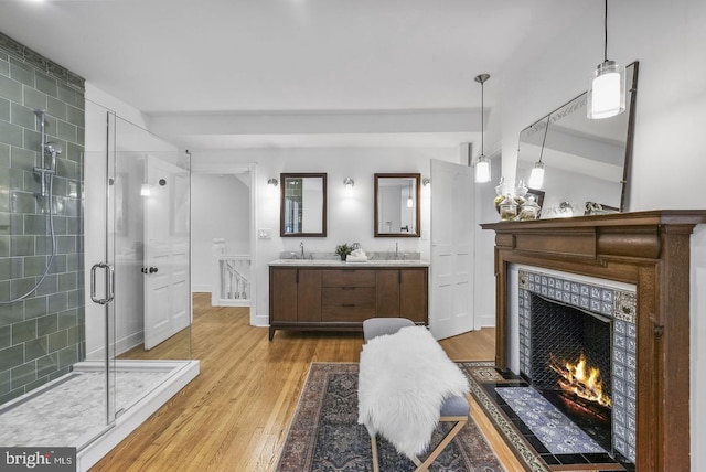 bathroom featuring vanity, a fireplace, a shower with shower door, and hardwood / wood-style floors