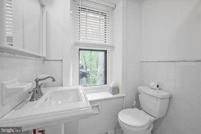 bathroom featuring tile walls, sink, and toilet