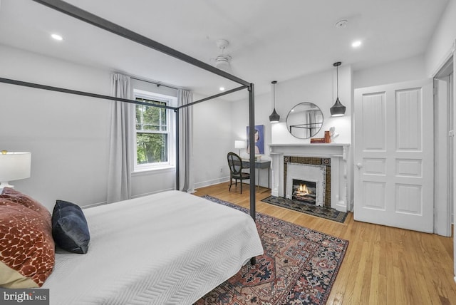 bedroom with light hardwood / wood-style floors and a tile fireplace