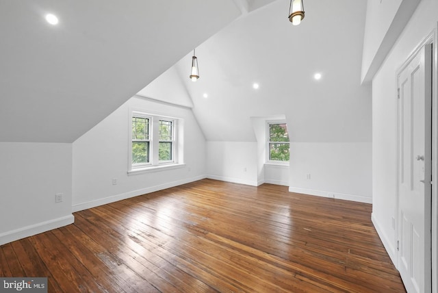 additional living space with lofted ceiling, a healthy amount of sunlight, and dark hardwood / wood-style flooring