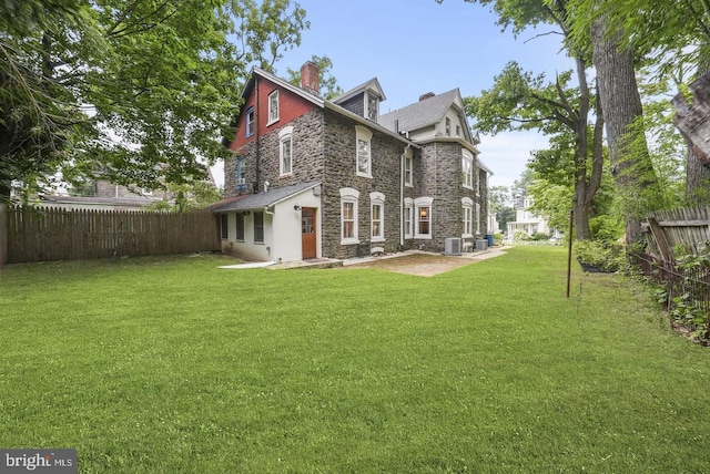 rear view of property with a yard, a patio area, and central air condition unit