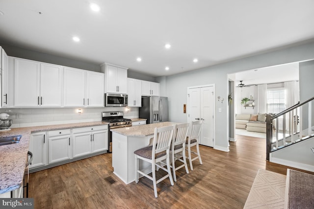 kitchen with visible vents, dark wood-style floors, a center island, backsplash, and stainless steel appliances