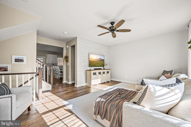 living area featuring baseboards, ceiling fan, stairs, and wood finished floors
