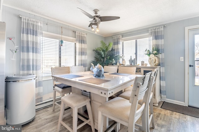 dining space featuring ceiling fan, light hardwood / wood-style flooring, and a textured ceiling