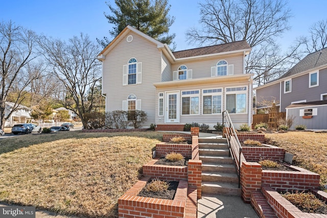 view of front of property with a sunroom and a front lawn