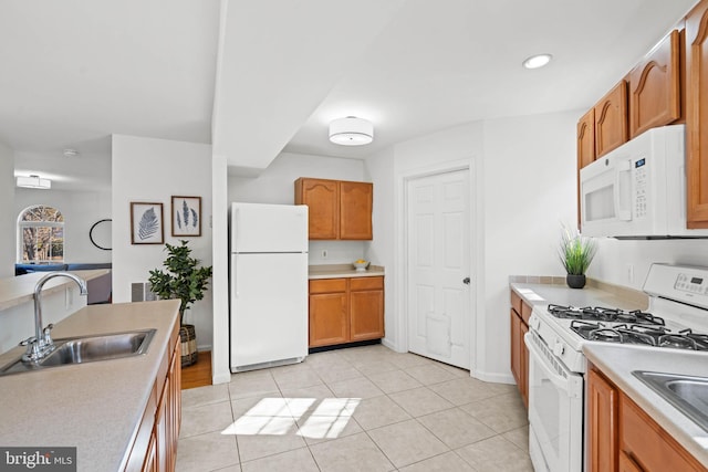 kitchen featuring light tile patterned floors, white appliances, a sink, light countertops, and brown cabinetry