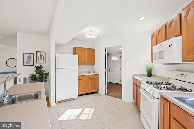 kitchen featuring light tile patterned floors, white appliances, a sink, light countertops, and brown cabinetry