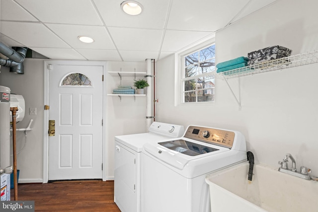 clothes washing area featuring laundry area, a sink, baseboards, washer and dryer, and dark wood finished floors