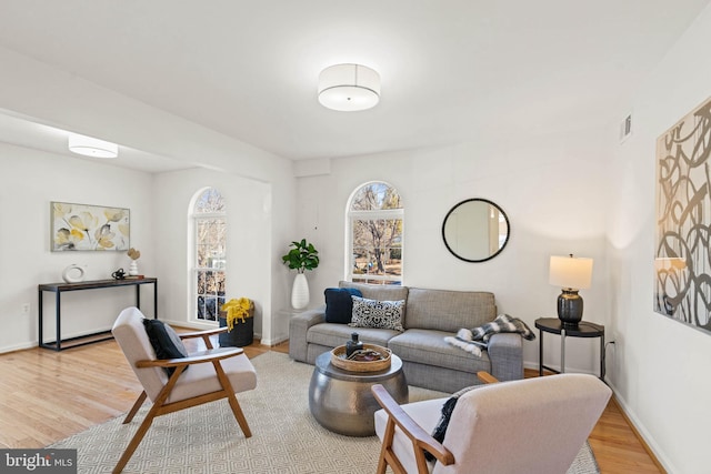 living room with light wood-style floors, visible vents, and baseboards