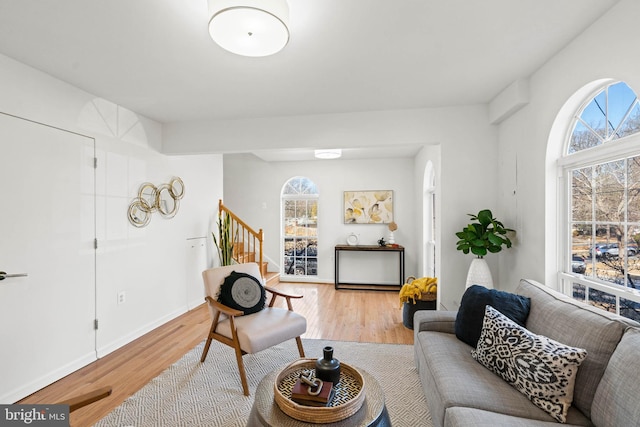 living room with light wood-type flooring, plenty of natural light, and stairs