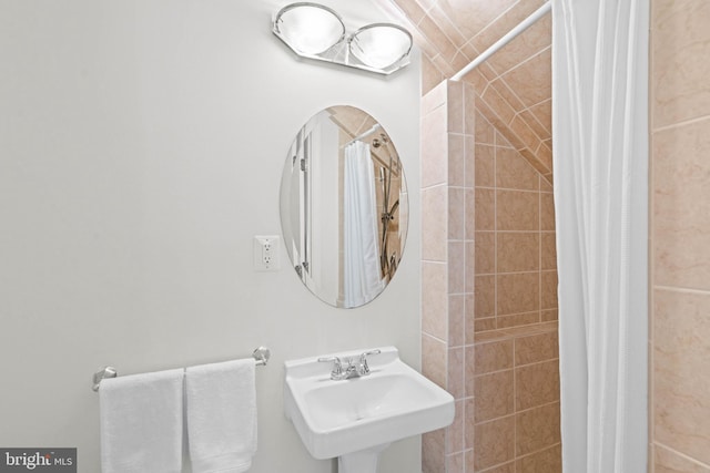 bathroom with tiled shower and a sink